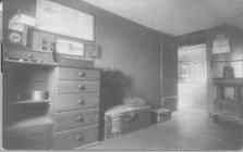 SA1405.17 - Shows the interior of an unidentified room with stove, case of drawers, trunks, etc.